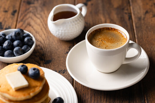 Coffee espresso and blueberry pancakes on old wooden table