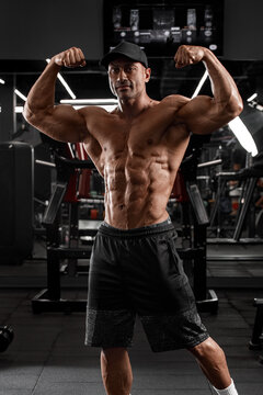 Muscular man in gym showing muscles. Strong male naked torso abs