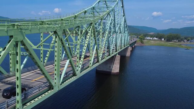 Drone footage moving along the metal structure of the J.C. Van Horne cantilever bridge, capturing traffic flowing between Campbellton, New Brunswick, and the Listuguj Mi'gmaq reserve in the Gasp&eacute; Peni