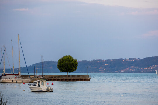 Paysage paisible du lac de Neuch&acirc;tel avec un petit voilier amarr&eacute;, une jet&eacute;e et les collines du littoral en arri&egrave;re-plan.