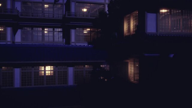 Quiet wooden ryokan corridor at night, lanterns lining passage, sliding doors, shadows of garden trees and reflective puddles for intimate traditional stay