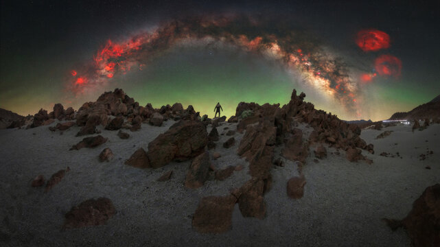 View of a person standing on the volcanic rocky terrain of the Mines of San Jose under a vibrant Milky Way and night sky in Santa Cruz de Tenerife, Canary Islands, Spain.