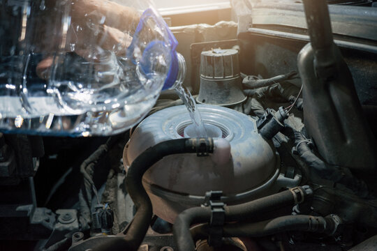 Antifreeze coolant pouring into car reservoir for radiator cooling system maintenance and refill.
