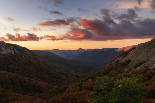 View of the Terminillo mountain range during a vibrant sunset with autumn foliage covering the slopes in Rieti, Lazio, Italy.