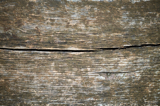 Close-up of an old weathered wooden surface with natural grain, deep cracks, rough texture and earthy brown tones. Rustic timber background with authentic aged character