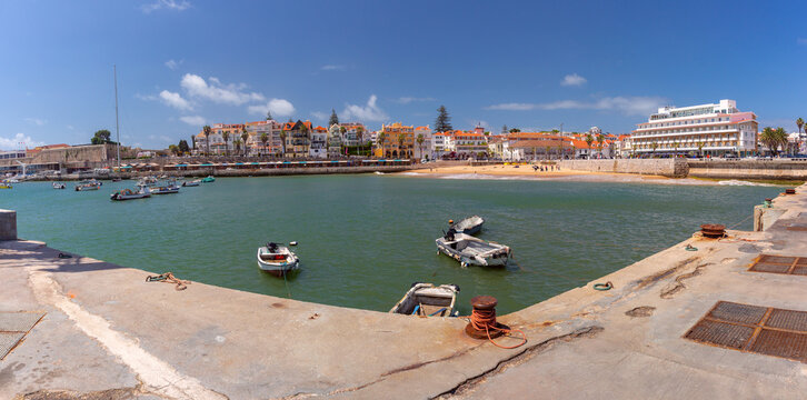 Coastal view of Cascais with small boats, sandy beach and traditional buildings along the Atlantic shore in Portugal.