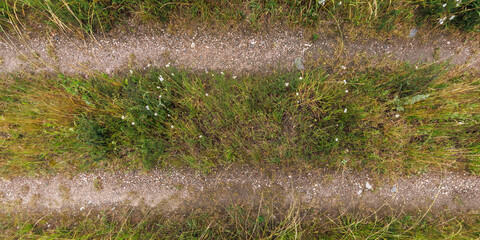 view from above on texture of gravel road among grass field
