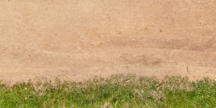 view from above on texture of gravel road among grass field