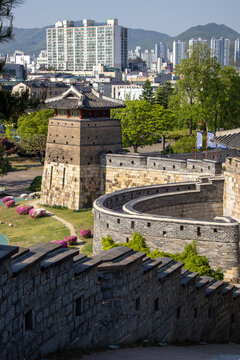 Historic fortress wall and watchtower contrasting with modern high-rise buildings in the background