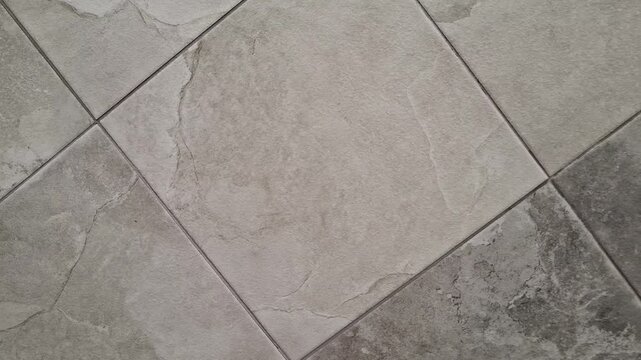 Large gray ceramic floor tiles arranged in a geometric pattern, modern flooring, interior renovation, construction materials, and home design.