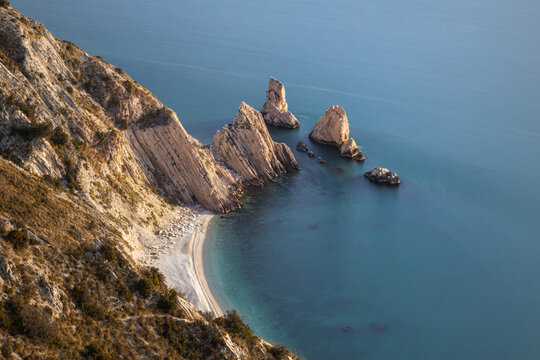 View of Two Sisters Beach with its iconic white limestone sea stacks, turquoise water, and rugged cliffs along the Adriatic coast in Sirolo, Marche, Italy.