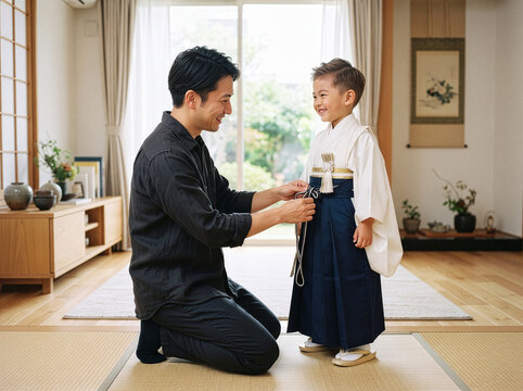 Father kneeling to dress son in hakama for Shichi Go San at home