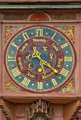 Fototapeta premium Detailed view of the historic astronomical clock on the facade of Strasbourg Cathedral, featuring an ornate clock face, Roman numerals, zodiac symbols, decorative figures and Gothic stonework.