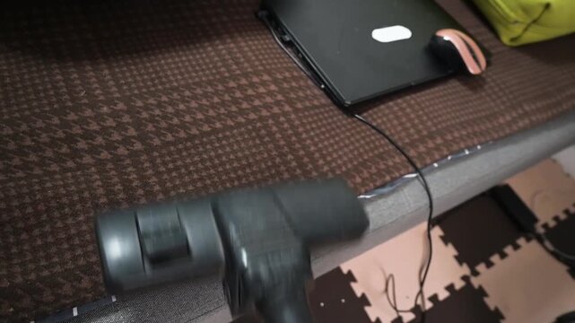 Cleaning Sofa Upholstery with Vacuum Cleaner Brush Near Laptop on Brown Fabric
