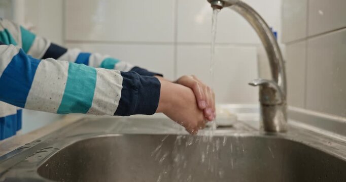 Kid boy wash hands in sink in kitchen. 4K 10-bit