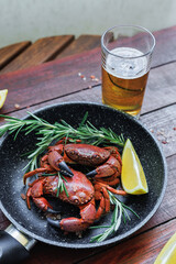 Cooked crabs served with a glass of cold beer, rosemary and lemon in a skillet, traditional seafood meal, casual dining and pub cuisine concept © svittlana