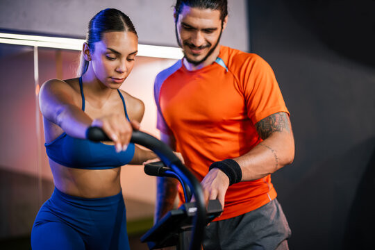 Medium shot of an athletic man and woman smiling and posing together after completing a challenging workout session in a gym.