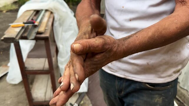 Close up of male dirty hands of adult labor at construction. Repairman rubbing unclean arms after hard work at the site. Concept of exhausting and hard work. Slow motion