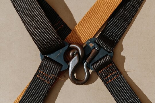 Fall-arrest harness webbing with a forged snap hook and buckle, featuring woven textures and warm copper tones for safety training and PPE supply, with copy space
