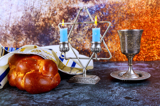 Jewish ritual objects with challah bread wine cup on table for Shabbat celebration