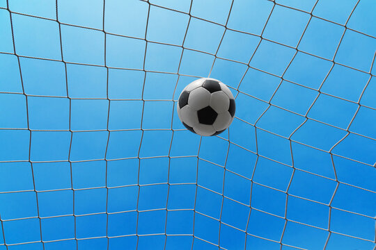  Soccer ball in soccer goal net . Close-up textured soccer net on soccer goal isolated on free sky background.