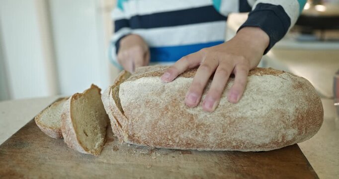 Kid hands cut bread with knife. Boy help in kitchen. 4K 10-bit