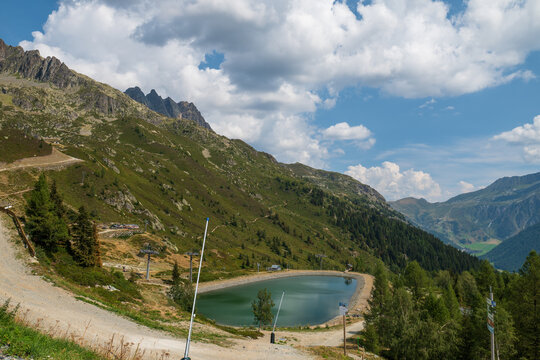 Turquoise mountain lake, rugged green slopes and cloud-filled sky in the French Alps near Chamonix.