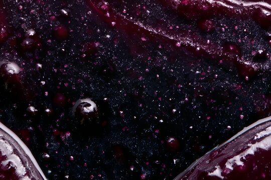 Details of a dark berry jam with visible fruit pieces and glistening texture in a close-up view