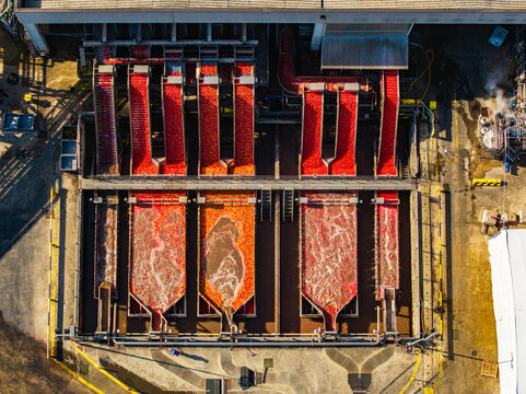 Aerial view of tomato processing factory with conveyor belts and water channels for washing fresh produce at a food factory in Pomposa, Emilia-Romagna, Italy.