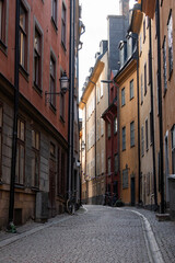 Fototapeta premium Stockholm, Sweden : Narrow cobblestone street in Gamla Stan lined with historic buildings, traditional lanterns and bicycles in Stockholm’s Old Town.