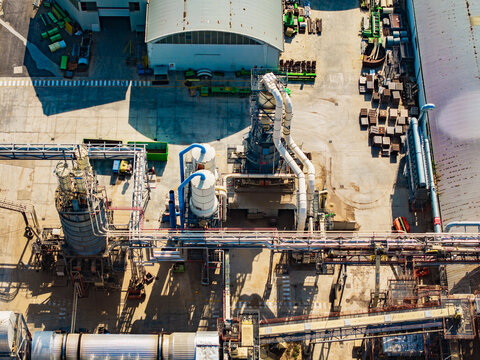 Aerial view of a modern food factory featuring industrial processing equipment, large storage tanks, complex piping systems, and a concrete yard in Pomposa, Emilia-Romagna, Italy.