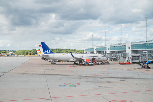 Stockholm, Sweden &mdash; August 1, 2026: SAS passenger aircraft parked at an airport gate while ground crews service the plane beside the terminal.