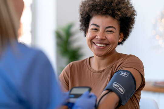 Smiling Black woman receives a blood pressure test from a clinician. Health screening, medical care, patient comfort.