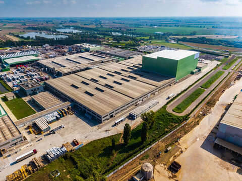 Aerial view of a large food factory complex with expansive industrial rooftops, loading docks, and surrounding agricultural fields in Pomposa, Emilia-Romagna, Italy.