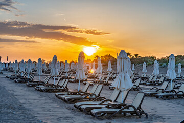 Fototapeta premium Mediterranean sunset with long rows of sun loungers and beach umbrellas in Antalya, Turkey.