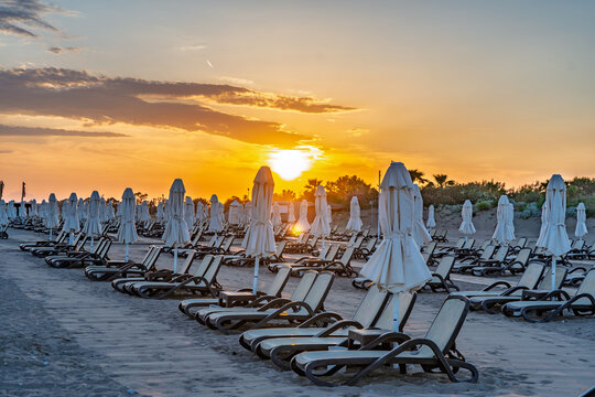 Mediterranean sunset with long rows of sun loungers and beach umbrellas in Antalya, Turkey.