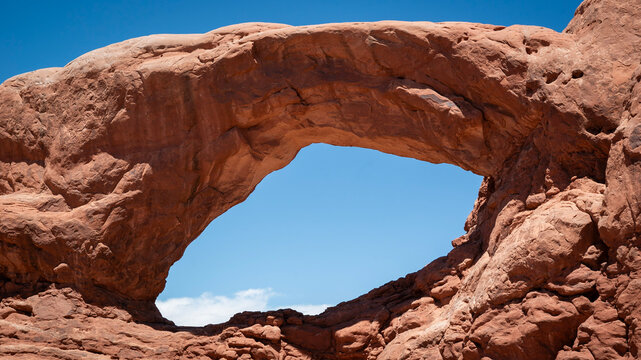 A dramatic sandstone arch frames the blue sky in Arches National Park