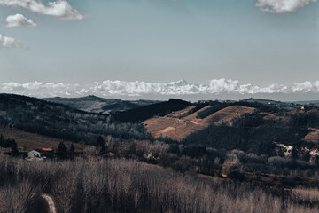 Wide rural landscape with rolling hills, winter fields, distant mountains, cloudy sky, soft daylight, and layered horizon creating calm natural scenery for travel and outdoor themes © Ivan