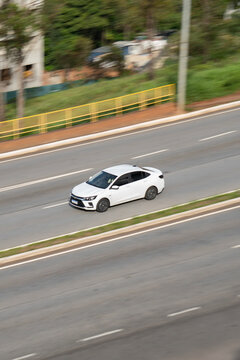 White Chevrolet Onix side profile moving, Compact sedan driving on highway