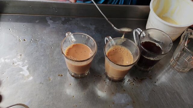 Two Small Glass Cups of Traditional Milk Tea Served on a Rustic Metal Tray