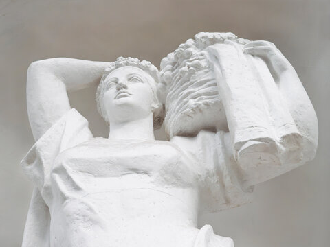 Classical white plaster statue of a woman carrying a fruit basket, low angle view
