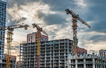 Tower cranes working on modern residential building construction site against dramatic cloudy sky © LemPro Filming Life