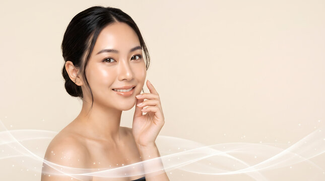 Asian woman touching cheek with radiant skin against beige background and soft flowing white wave