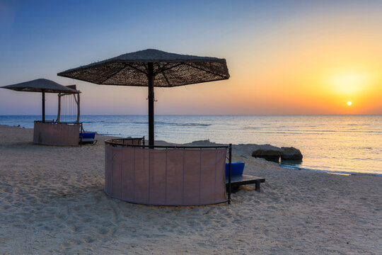 Sunbeds with umbrellas on the beach in Marsa Alam at sunrise, Egypt