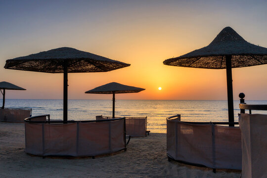 Sunbeds with umbrellas on the beach in Marsa Alam at sunrise, Egypt