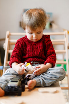 Focused Toddler Boy Playing with Busy Cube Wooden Sensor Toy Sitting in Kids Playroom. Motor skills play and development