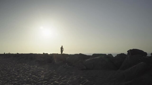 France, Valras Plage August 08, 2026 &mdash; Silhouette of a lonely man fishing on the rocky sea pier at golden hour sunset