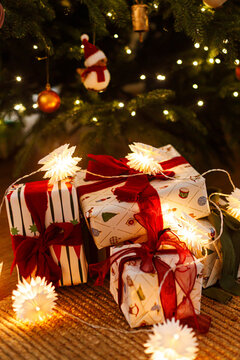 Beautifully Wrapped Christmas Presents with Red Ribbons and Glowing Star Lights Under Christmas Tree. Merry Christmas. Xmas wallpaper