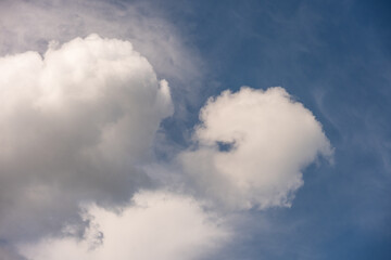 Obraz premium Fluffy white cumulus clouds in a dark blue sky, as a texture pattern nature background 