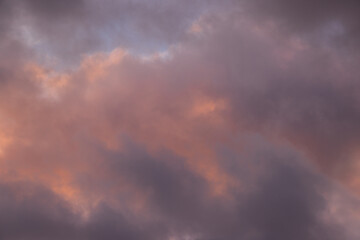 Obraz premium Moody dusk clouds with subtle pink and purple pastel tones illuminated by warm light. Dramatic atmospheric sky background perfect for artistic overlays, wallpapers, and creative design projects.